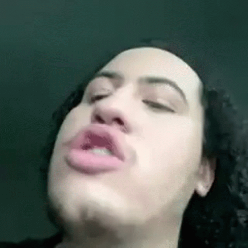 A Man With Curly Hair Is Making A Funny Face With His Eyes Closed And His Mouth Open . GIF