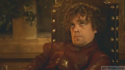 A Man With Curly Hair Is Sitting In A Chair And Making A Face . GIF