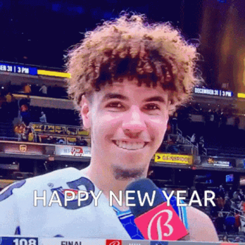 a man with curly hair is smiling and holding a microphone with the words happy new year written below him