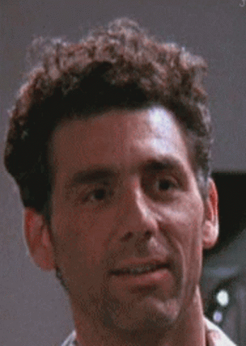 A Man With Curly Hair Is Smiling For The Camera . GIF