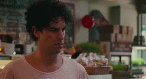 Man With Curly Hair Standing At Store Counter GIF