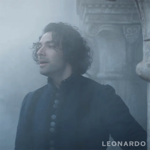 A Man With Curly Hair Is Standing In Front Of A Pillar With The Word Leonardo On The Bottom GIF