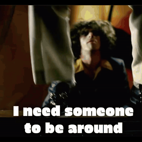 Curly-Haired Man In Front Of I Need Someone To Be Around Sign GIF
