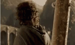A Man With Curly Hair Is Standing In Front Of A Wooden Post . GIF