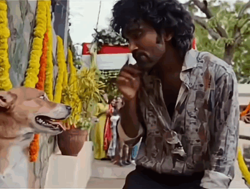 A Man With Curly Hair Is Talking To A Dog That Is Looking At Him GIF