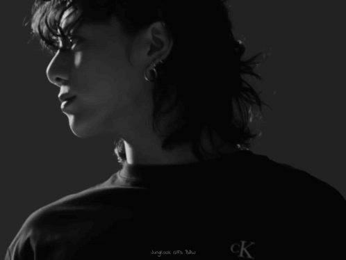 A Man With Curly Hair Is Wearing A Black Shirt That Says Calvin Klein Jeans GIF