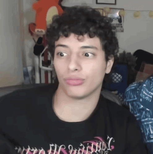 A Man With Curly Hair Is Wearing A Black Shirt That Says ' Nightmare ' GIF