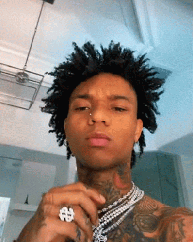 A Man With Curly Hair Is Wearing A Ring And A Necklace . GIF