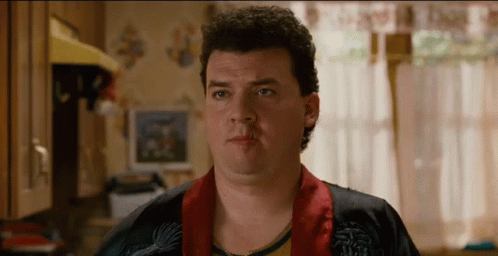 A Man With Curly Hair Is Wearing A Robe And Looking At The Camera GIF