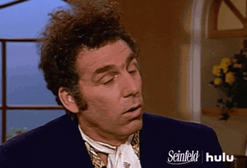 A Man With Curly Hair Is Wearing A Seinfeld Advertisement GIF