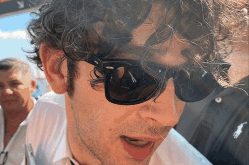 A Man With Curly Hair Is Wearing Sunglasses And A White Shirt GIF