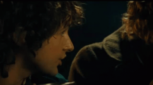 A Man With Curly Hair Says " I 'M Sharing It " In A Dark Room GIF