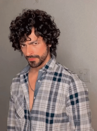 A Man With Curly Hair Wearing A Plaid Shirt GIF