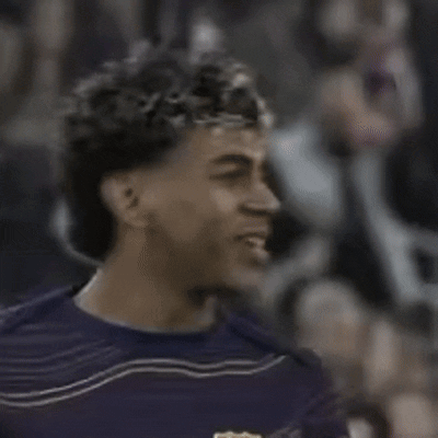 a man with curly hair wearing a purple shirt is smiling