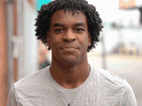 A Man With Curly Hair Wears A Grey Shirt GIF