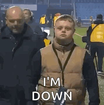 A Man With Down Syndrome Is Standing In Front Of A Group Of People On A Field . GIF