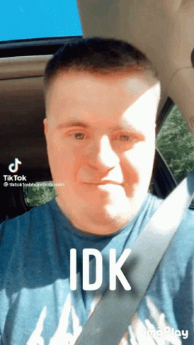 A Man With Down Syndrome Is Wearing A Blue Shirt And A Seat Belt GIF