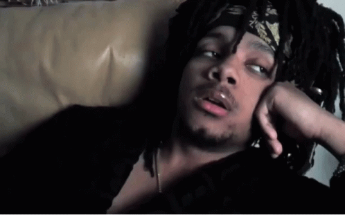 A Man With Dreadlocks And A Bandana On His Head Is Laying On A Couch GIF