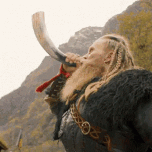 A Man With Dreadlocks And A Beard Is Blowing A Horn . GIF