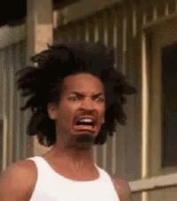 A Man With Dreadlocks And A Beard Is Making A Funny Face While Wearing A White Tank Top . GIF