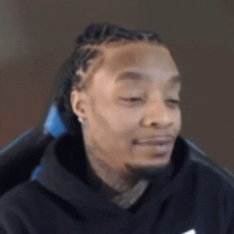 A Man With Dreadlocks And A Beard Is Sitting In A Chair Making A Funny Face . GIF