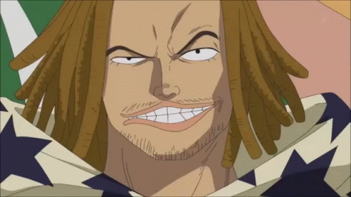 A Man With Dreadlocks And A Beard Is Smiling With A Flag In The Background GIF