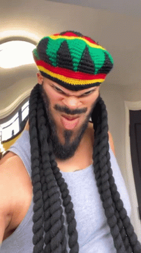 A Man With Dreadlocks And A Beard Wearing A Hat GIF