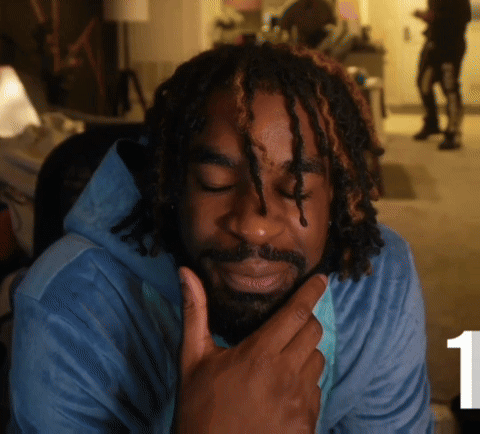 A Man With Dreadlocks And A Beard Wears A Blue Shirt GIF