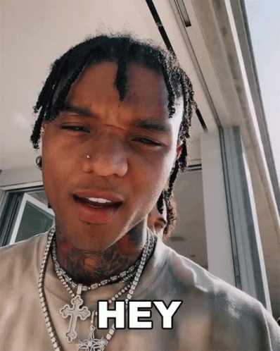 A Man With Dreadlocks And A Cross Necklace Says " Hey " GIF