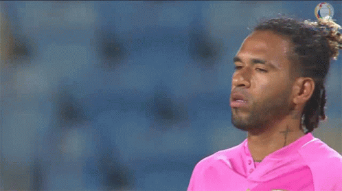 A Man With Dreadlocks And A Cross Tattoo On His Neck Is Wearing A Pink Shirt GIF
