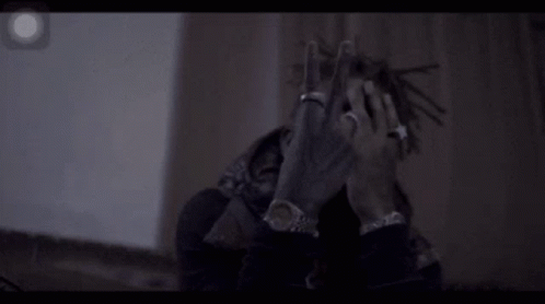 A Man With Dreadlocks And A Ring On His Finger Is Making A Peace Sign . GIF
