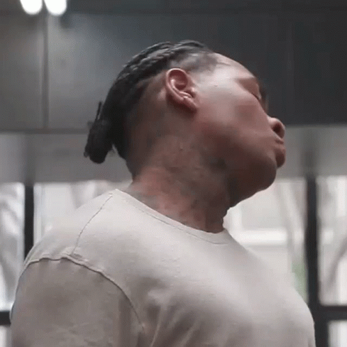 a man with dreadlocks and a tattoo on his neck is looking down