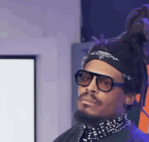 A Man With Dreadlocks And Glasses Is Wearing A Headband And A Bandana . GIF