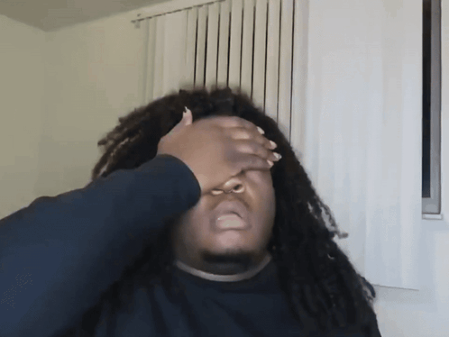 a man with dreadlocks has his hand on his face
