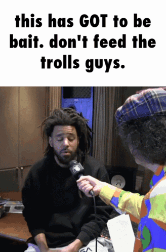 A Man With Dreadlocks Is Being Interviewed By A Man In A Clown Hat GIF