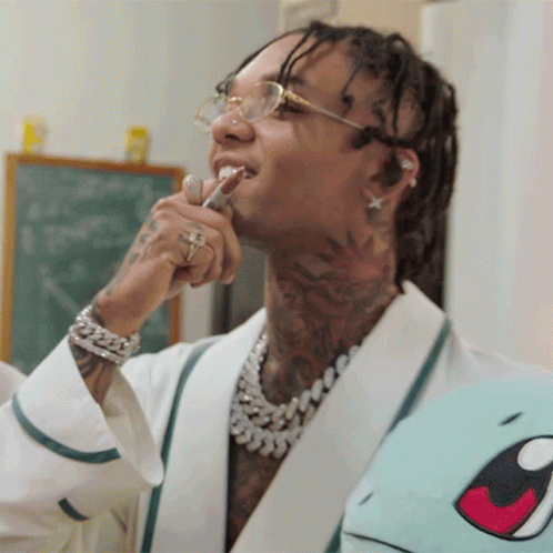 A Man With Dreadlocks Is Brushing His Teeth While Wearing Glasses GIF