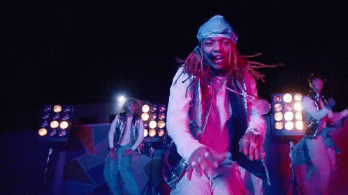 A Man With Dreadlocks Is Dancing On A Stage In Front Of A Crowd . GIF