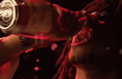 A Man With Dreadlocks Is Drinking From A Bottle That Says ' Red ' On It GIF