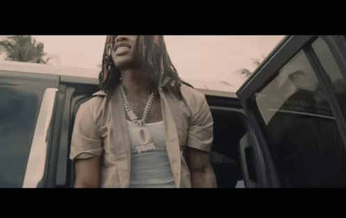 A Man With Dreadlocks Is Getting Out Of A Car And Wearing A Tank Top That Says ' Rick ' On It GIF