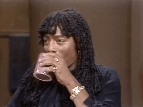 A Man With Dreadlocks Is Holding A Cup Of Coffee In His Hand . GIF
