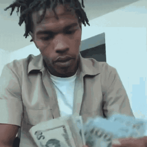 A Man With Dreadlocks Is Holding A Stack Of Money In His Hands . GIF