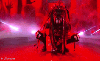 A Man With Dreadlocks Is Holding A Sword In Front Of A Crowd Of People In Red Lights . GIF