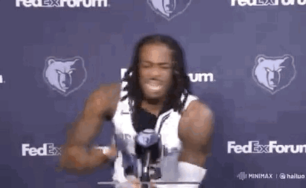 A Man With Dreadlocks Is Holding A Yellow Object In Front Of A Fedex Sign . GIF