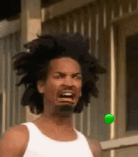 A Man With Dreadlocks Is Making A Funny Face While Looking At A Green Ball . GIF