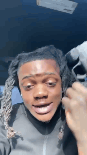 A Man With Dreadlocks Is Making A Funny Face While Sitting In A Car With His Mouth Open . GIF