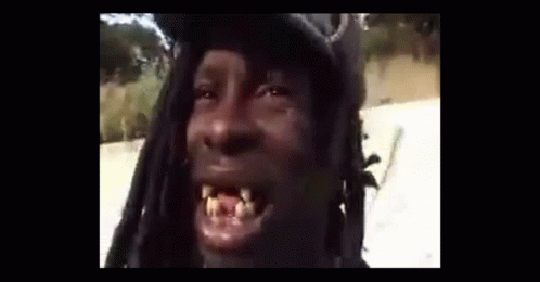 A Man With Dreadlocks Is Making A Funny Face While Wearing A Hat . GIF