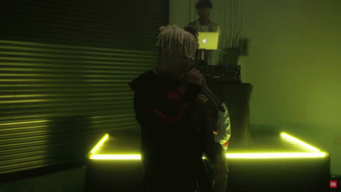 A Man With Dreadlocks Is Singing Into A Microphone With A Red Tnt Logo On The Bottom GIF