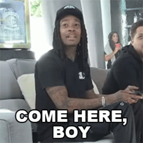 A Man With Dreadlocks Is Sitting On A Couch And Says Come Here , Boy . GIF