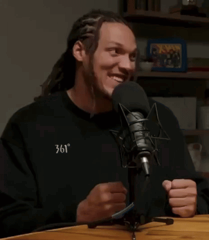 A Man With Dreadlocks Is Smiling In Front Of A Microphone With The Words It 'S Cam Johnson Above Him GIF