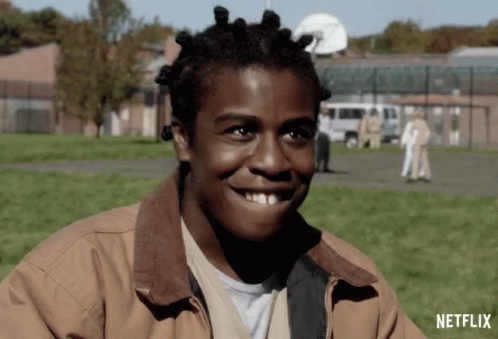 A Man With Dreadlocks Is Smiling In Front Of A Netflix Sign GIF